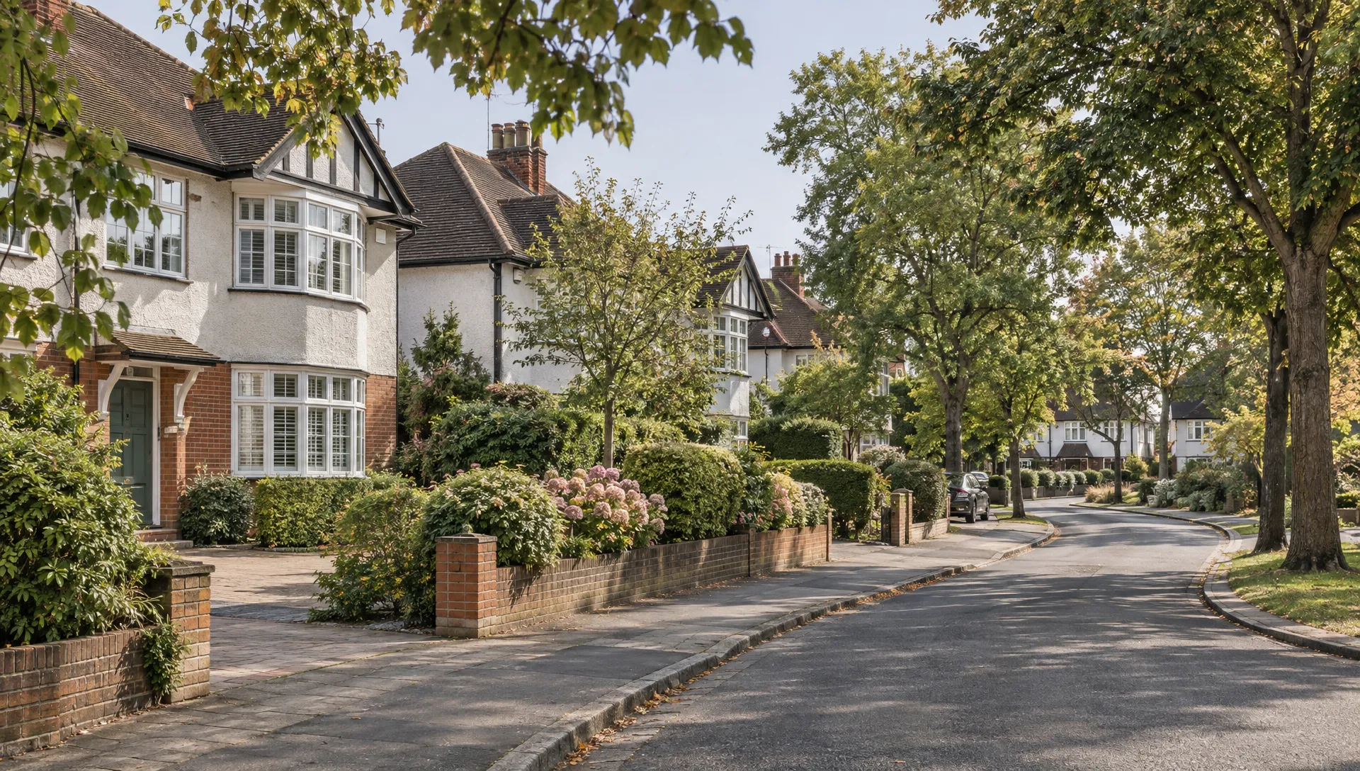 A quiet Ickenham residential street curves past 1930s semi-detached houses, mature trees and established front gardens, grounding a home sale in its local setting.