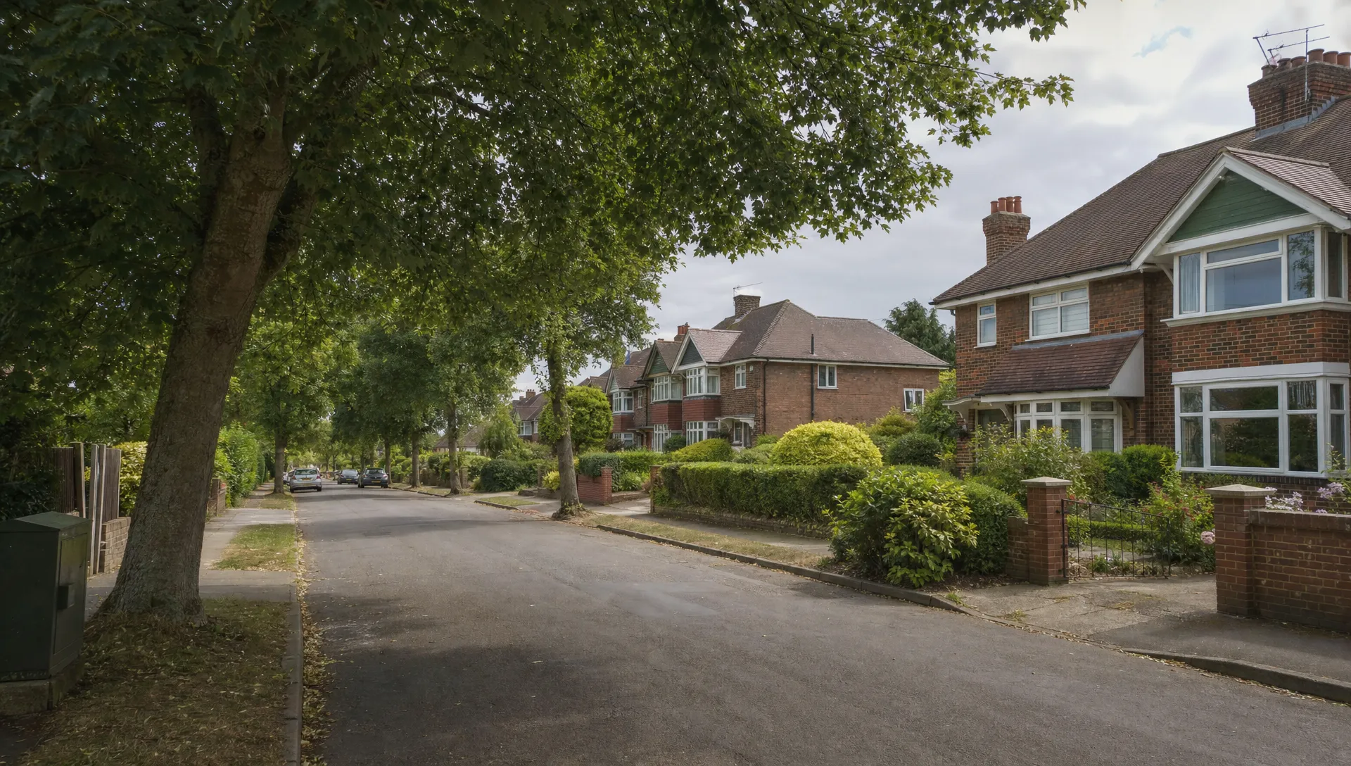 Tree-lined residential street near Swakeleys Road in Ickenham, with brick semi-detached homes and established front gardens, showing the setting for house-buying enquiries.